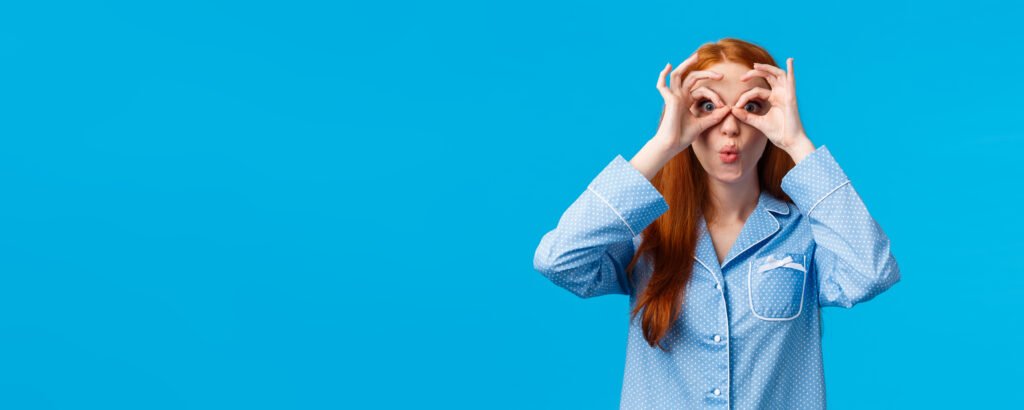 Indicateur 25 Qualiopi : quand l'innovation pédagogique s'inspire des neurosciences , source image : https://www.magnific.com/ Girl saying wow staring startled camera seeing great opportunity for special holidays discount. Attractive redhead female in pyjama looking through fingers and folding lips amused, blue background.